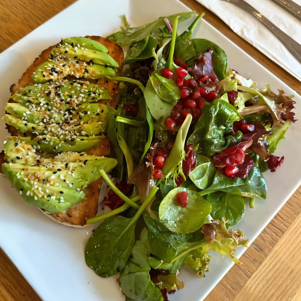Avocado toast with everything bagel seasoning and a side salad with pomegranate seeds.